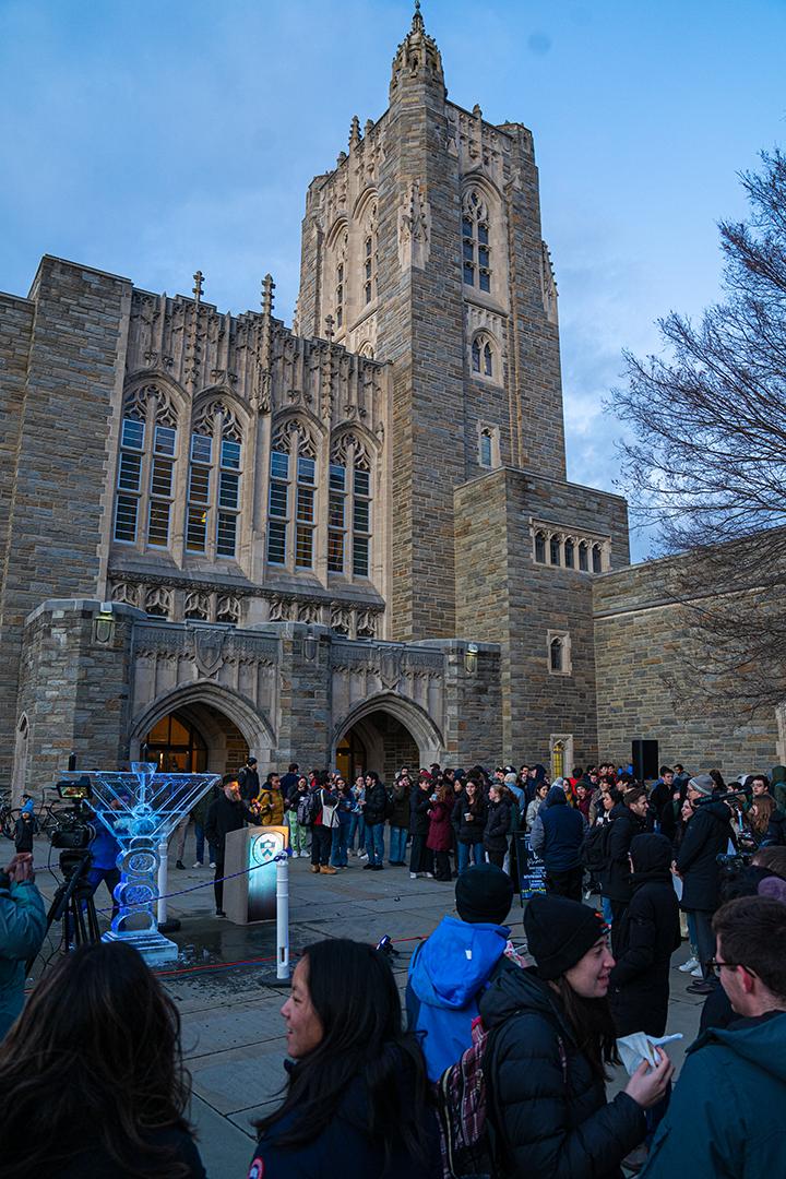 A view of Firestone Library with students gathered in front of the ice menorah.