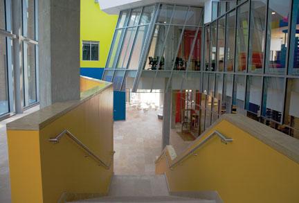 As seen from the front entrance, an atrium-passageway painted in brilliant colors divides the building in two. At right, the science library proper is visible behind its curtain wall of glass; at left are classrooms and offices.