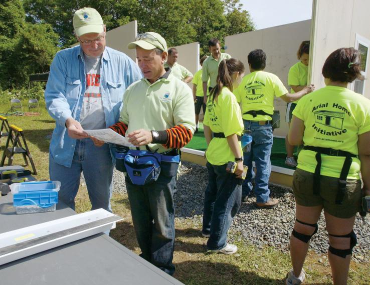  Tom Johnson '68, left, and Tom Pirelli '69, founder of the Arial Home Initiative, review plans to construct a prefab home as part of a service-project demonstration.