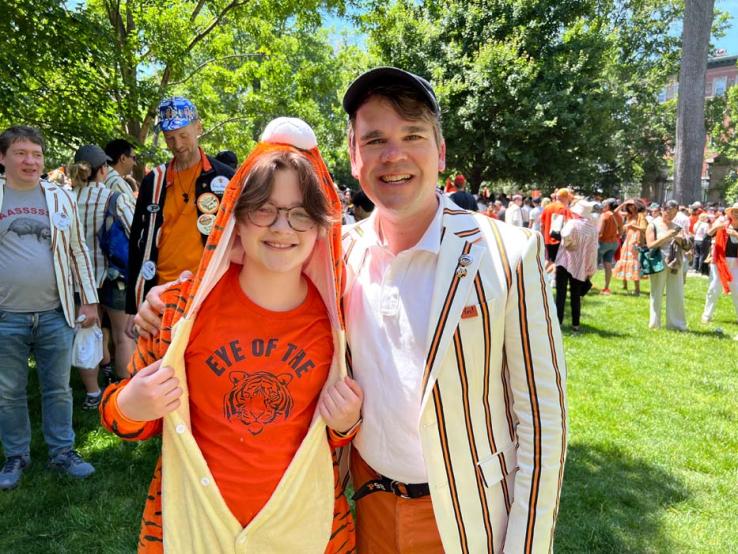A father and son; the son is wearing a tiger costume and a T-shirt that says "Eye of the Tiger."