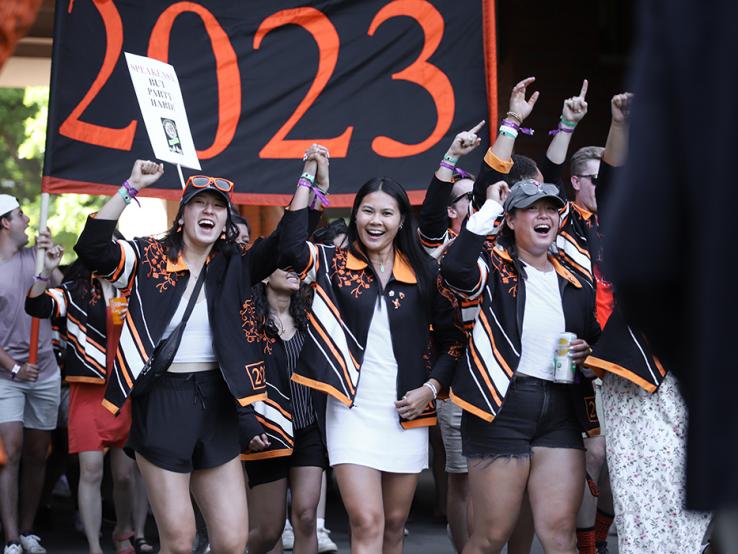 Women cheer in front of the "2023" banner.