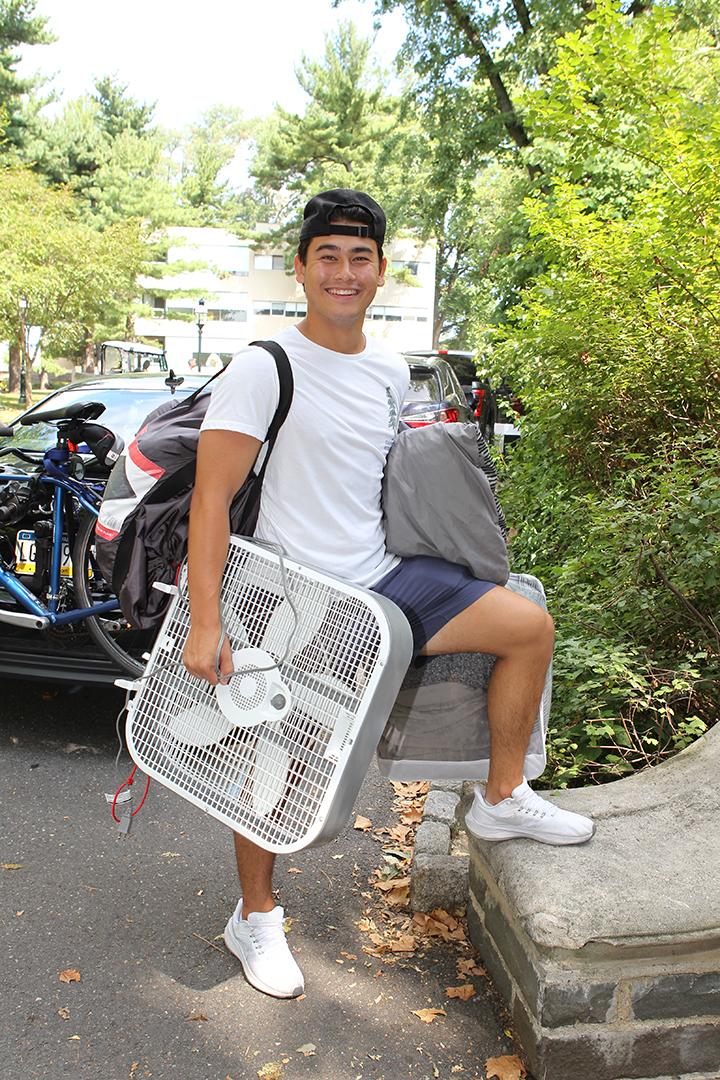 Jayden Sison ’26 holds an electric fan in one hand with a duffle bag over his shoulder.
