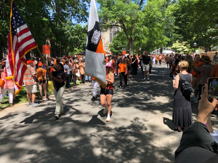 Alumni holding flags march in the P-rade.