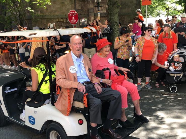 Two people sit on the back of a golf cart in the P-rade.