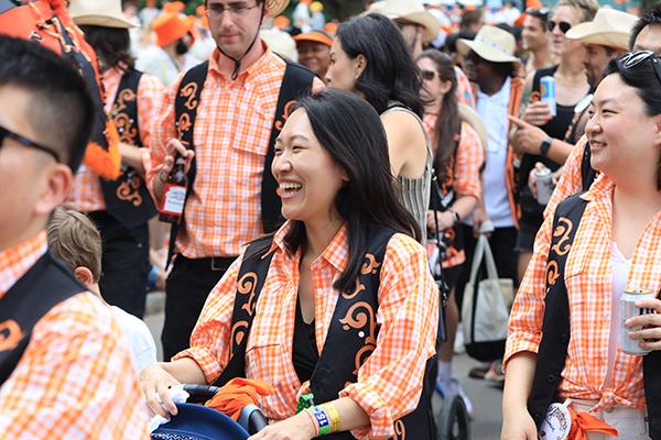 Alumni wearing orange plaid shirts march in the P-rade.