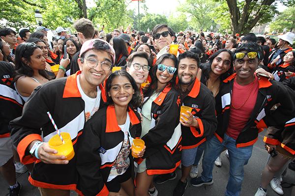 A group of young alumni hold drinks and pose for a photo at the P-rade.