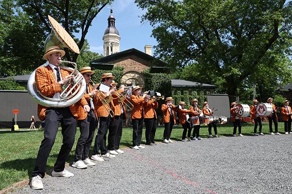 The marching band stands around the edge of the gravel circle on Cannon Green.