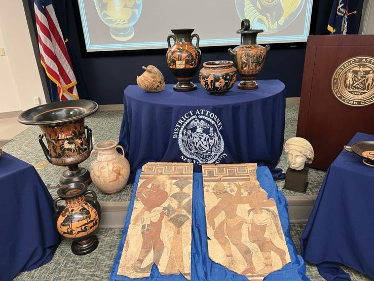 Tables with the Manhattan district attorney's seal, covered in red and black figure pottery.
