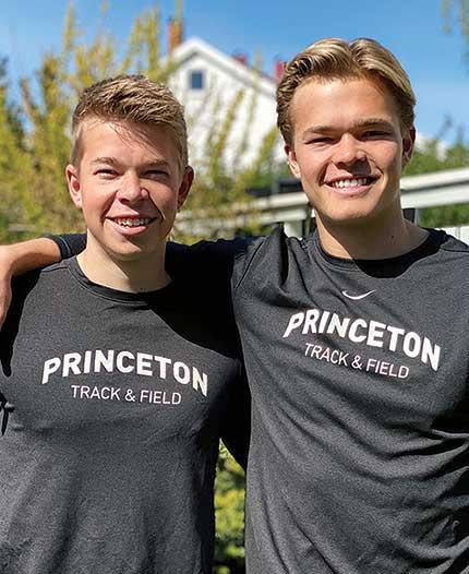 This is a headshot photo of Simen Guttormsen ’23, left, and Sondre Guttormsen ’23, both wearing gray "Princeton Track & Field" shirts with arms around each other's shoulders.