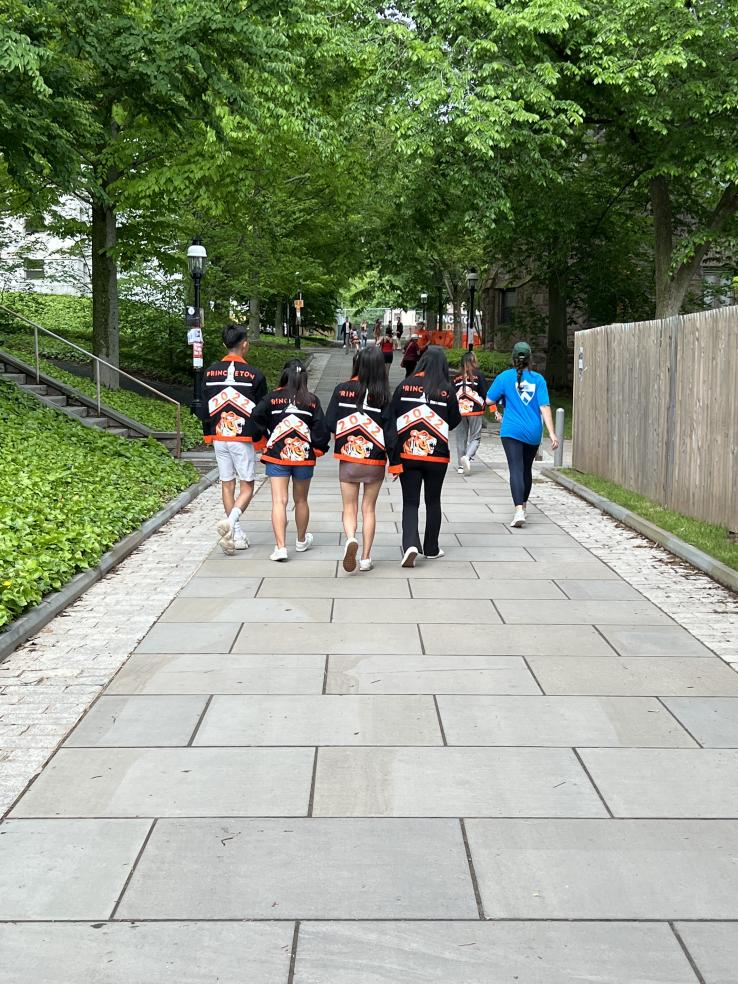 Four students in the Class of 2022 walk down a stone path with their class jackets on.