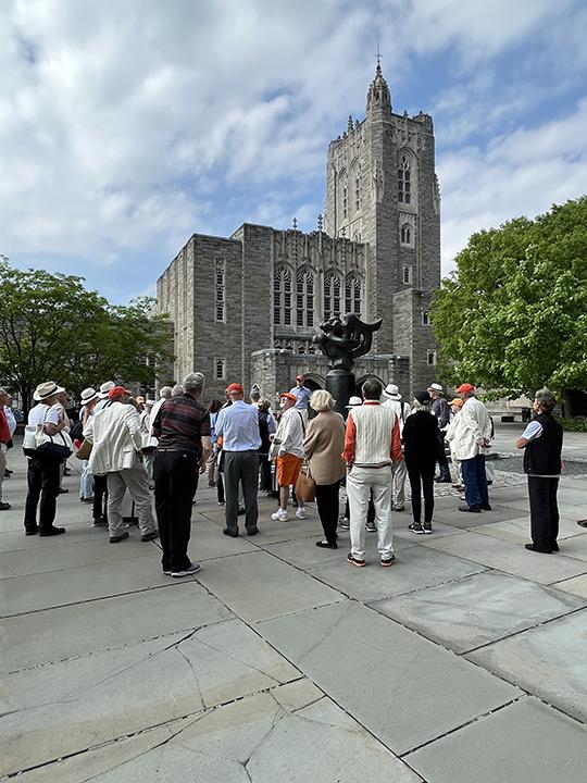 Alumni take a tour of campus with Firestone Library in the background.