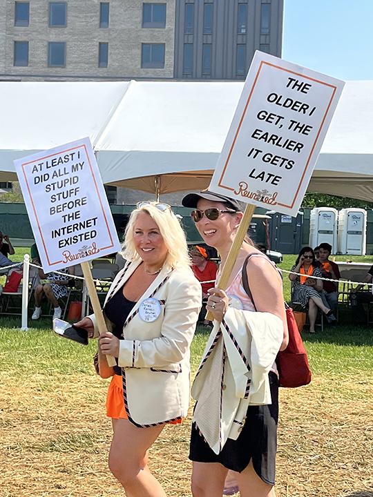 Two women carry signs that read, "At least I did all my stupid stuff before the Internet existed," and "The older I get, the earlier it gets late."