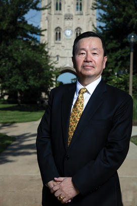 HIGHER ED_20200813_ChoiFormal_17_calim_toned (1) copy.jpg Mun Choi *92 standing outside in front of a Gothic college building.