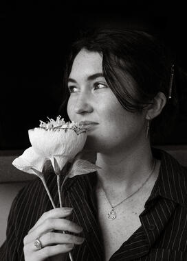 Black and white photo of Juju Lane holding a flower to her lips.