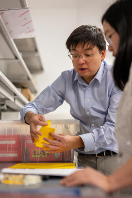 Tuo Zhao shows a student how to fold a piece of paper.