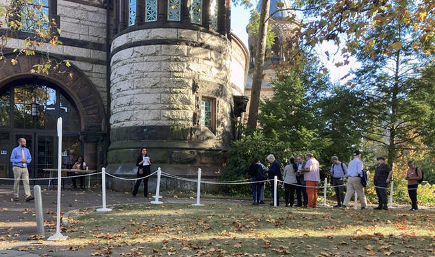 Faculty members standing in line outside a doorway