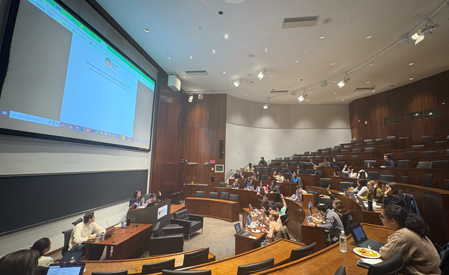 The USG meets in the Arthur Lewis Auditorium on Nov. 10. There is a document projected on the screen behind the USG Vice President. Members of the USG have their hands raised to vote.
