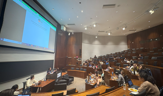 The USG meets in the Arthur Lewis Auditorium on Nov. 10. There is a document projected on the screen behind the USG Vice President. Members of the USG have their hands raised to vote.