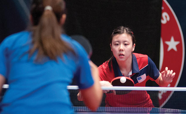 Two women play table tennis.