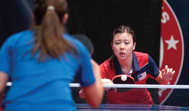 Two women play table tennis.