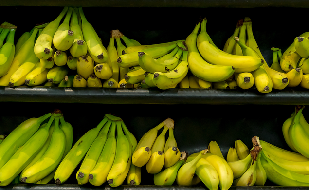 Green and yellow bananas on a grocery shelf