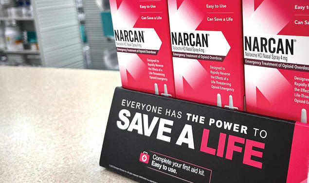 Pink boxes of Narcan tacked on counter with a sign that reads Save a Life