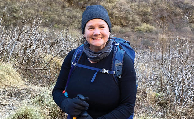 A woman smiles outdoors on a hike.