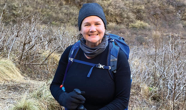 A woman smiles outdoors on a hike.