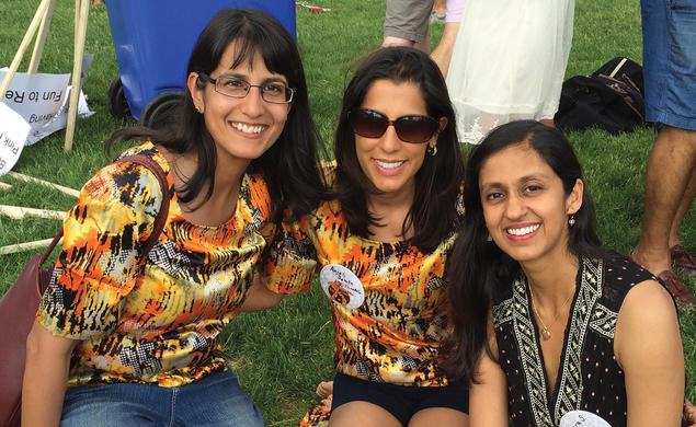 Three women sit on the grass.