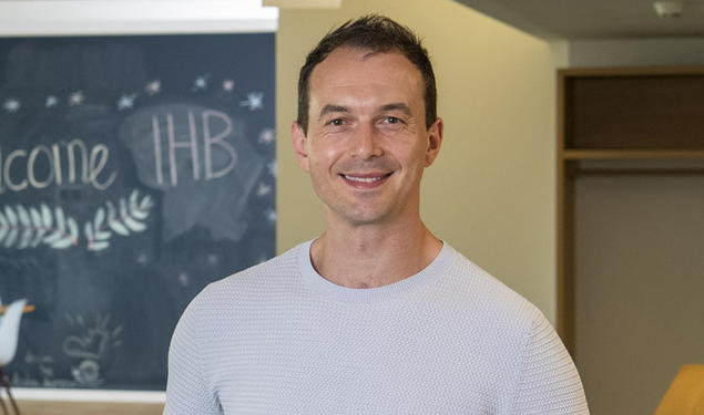 Headshot of a man with a chalkboard in the background.