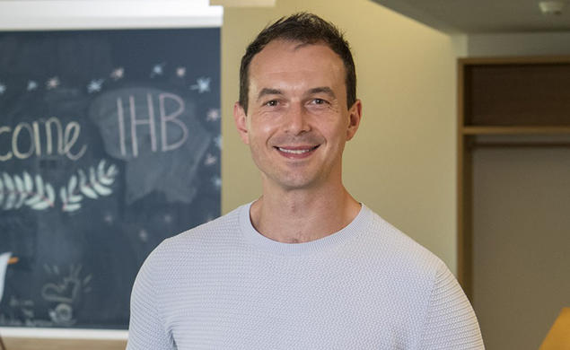 Headshot of a man with a chalkboard in the background.