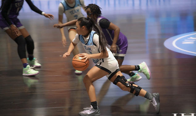Ashley Chea ’27 dribbles down the court in her blue-and-white high school basketball uniform.