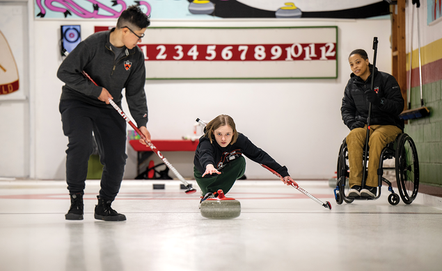 Three curling club members practice on the ice