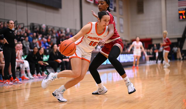 A Princeton basketball player dribbles inside, guarded tightly by a Harvard player. 
