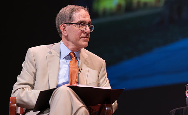 Princeton President Christopher Eisgruber ’83 holds an open binder on a stage.