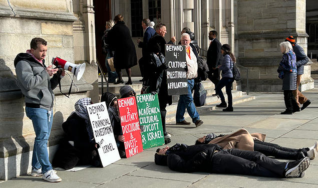 People walk into the Princeton chapel past a pro-Palestinian protest where two people are laying on the ground.