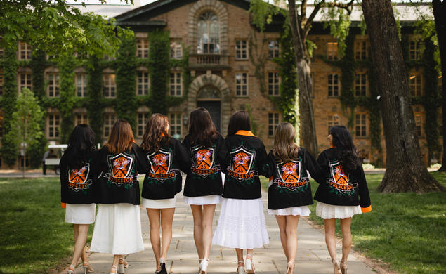 A group of Princeton women from the class of 2025 facing Nassau Hall while wearing their class jackets.
