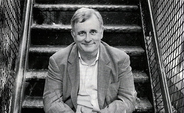 Edmund White sits on a fire escape in this black-and-white photo.
