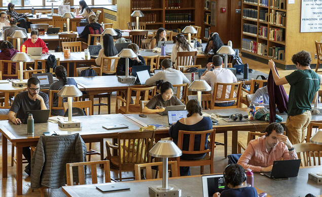 Students seated at library tables reading and studying