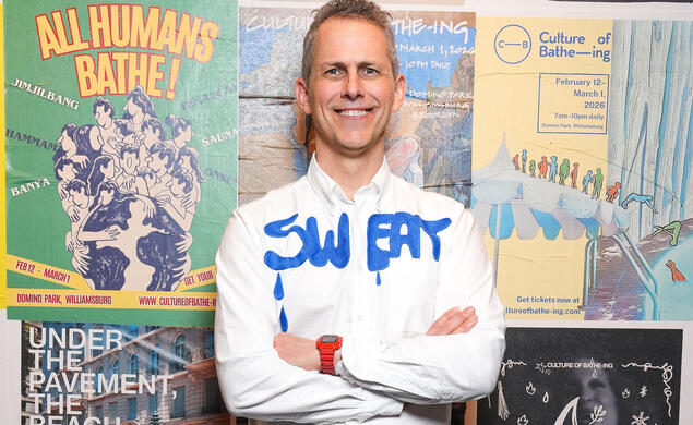 Robert Hammond &rsquo;92 stands with his arms crossed in front of various posters advertising his event, Culture of Bathe-ing