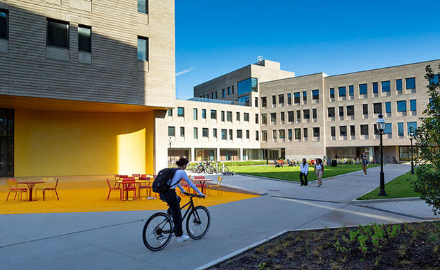 Student riding a bicycle next to dormitories