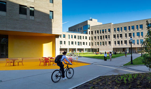 Student riding a bicycle next to dormitories