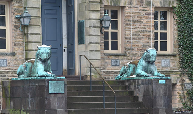 Two bronze tiger statues flank a door on a stone building, Princeton’s Nassau Hall.