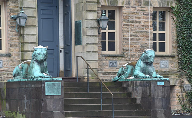 Two bronze tiger statues flank a door on a stone building, Princeton’s Nassau Hall.