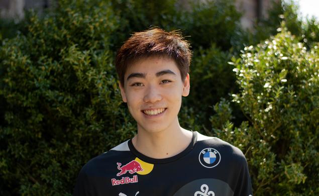 This is a headshot photo of Andrew Tang ’23 outside with shrubs in the background.