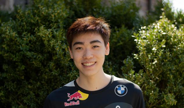 This is a headshot photo of Andrew Tang ’23 outside with shrubs in the background.