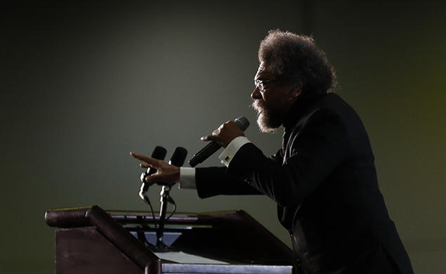 This is a photo of Cornel West, in profile, speaking at a podium.
