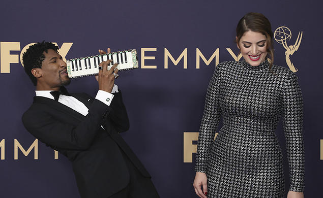 Suleika Jaouad ’10, right, and Jon Batiste arrive at the Emmy Awards on Sept. 22, 2019, in Los Angeles. Batiste plays a melodica while Jaouad laughs.