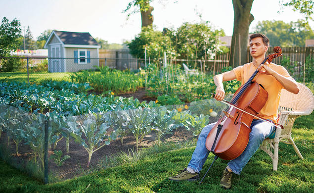 With his eyes shut, Calvin Van Zytveld ’19 plays a cello outdoors, a garden and a shed in the background.