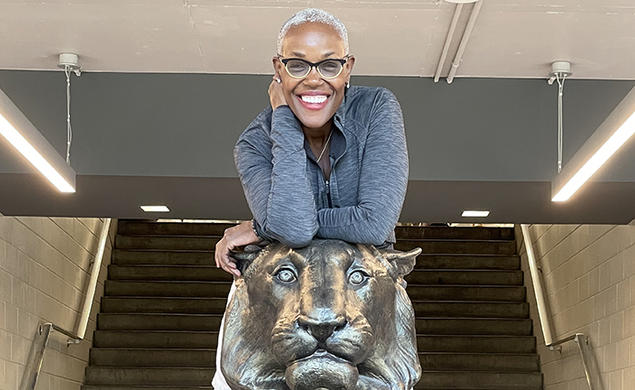 Deborah Saint Phard leans forward over a statue of a tiger.